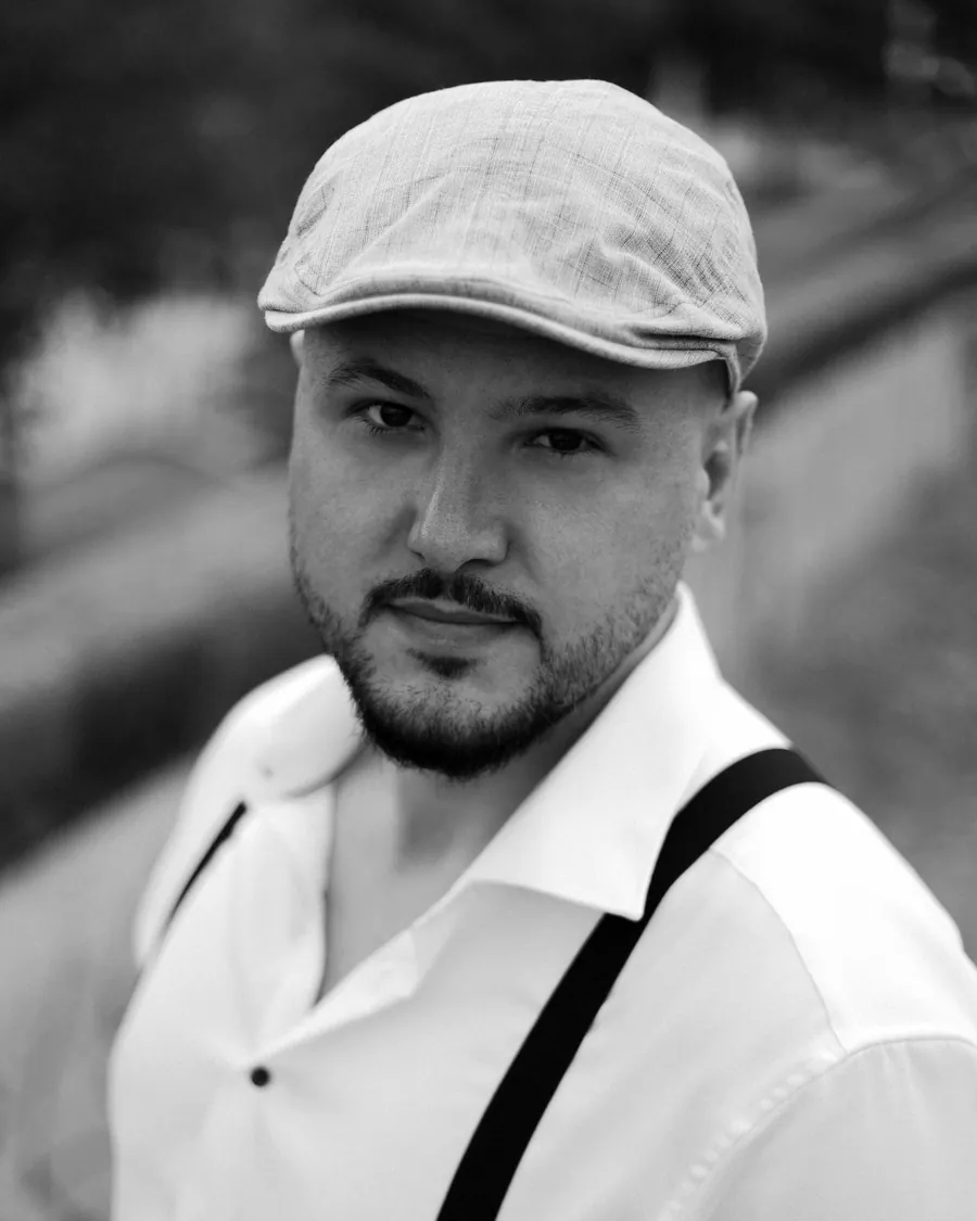 Юрій Довган у кашкеті й білій сорочці з підтяжками, портрет